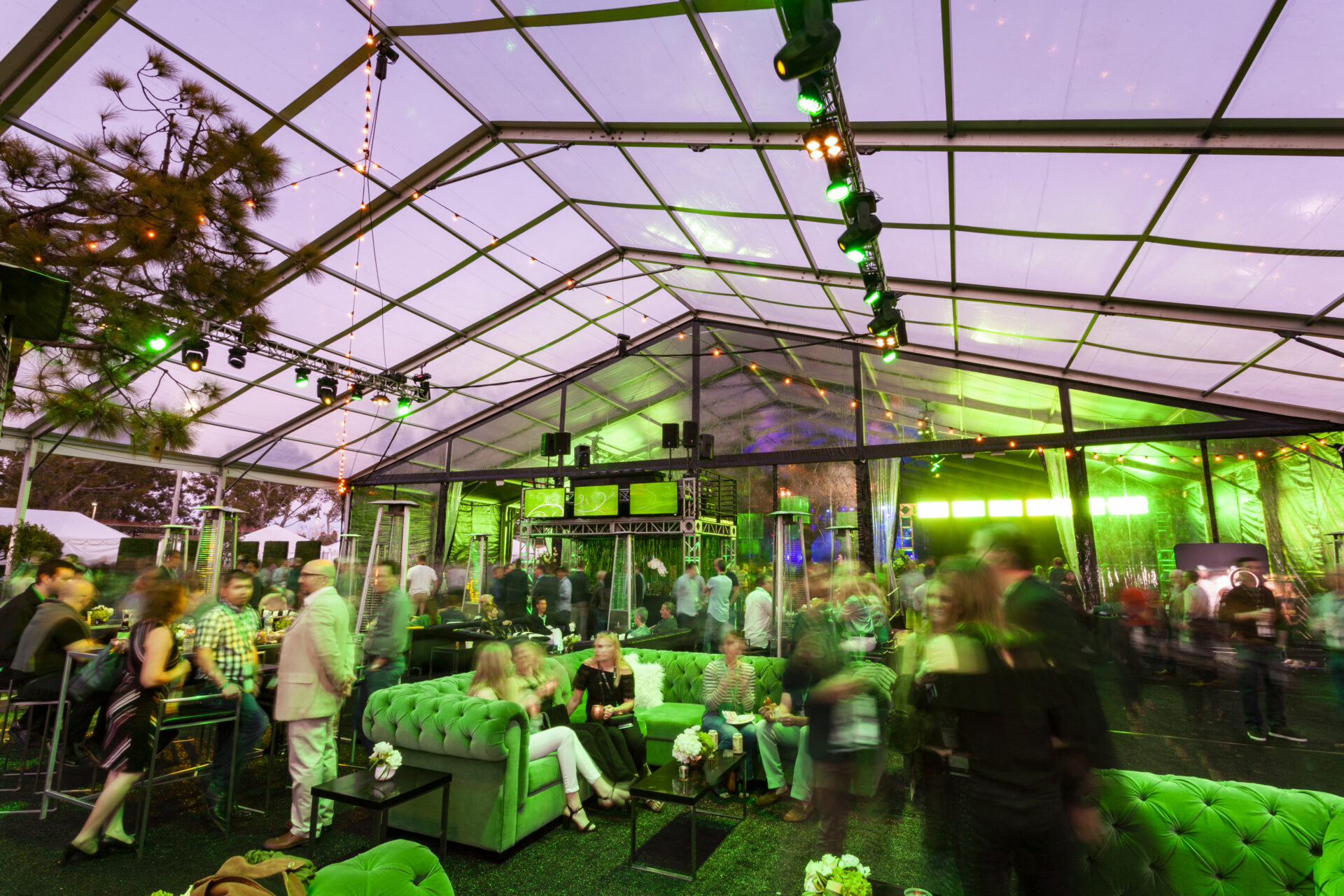Transparent tent with emerald lounge seating creates a chic, vibrant atmosphere